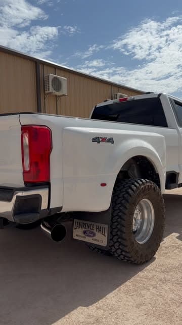 Rear view of a lifted white dually with a large exhaust tip